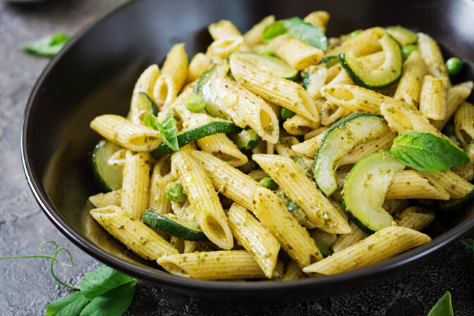 Penne pasta with pesto sauce, zucchini, green peas and basil. Italian food.