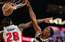 Porziņģa komandas biedrs Okongvu NBA dienas momentā paceļas gaisā un uzliek uz plakāta divus "Pistons" basketbolistus